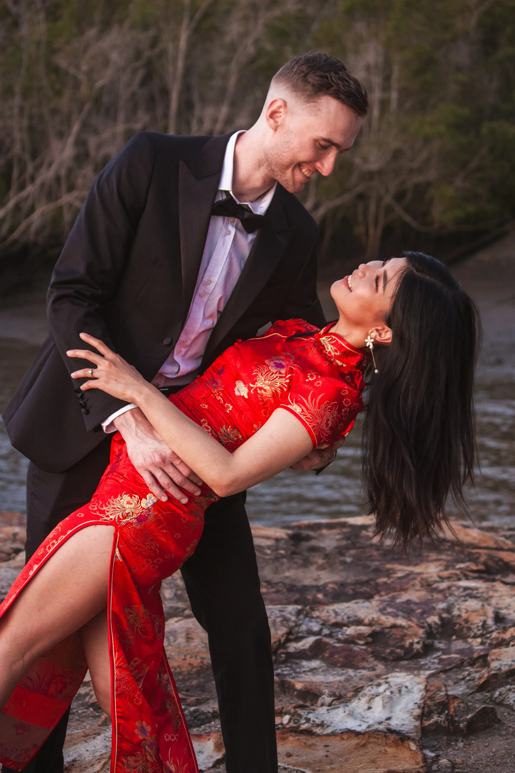 Joyful engagement photo with man dipping woman backwards in romantic outdoor setting