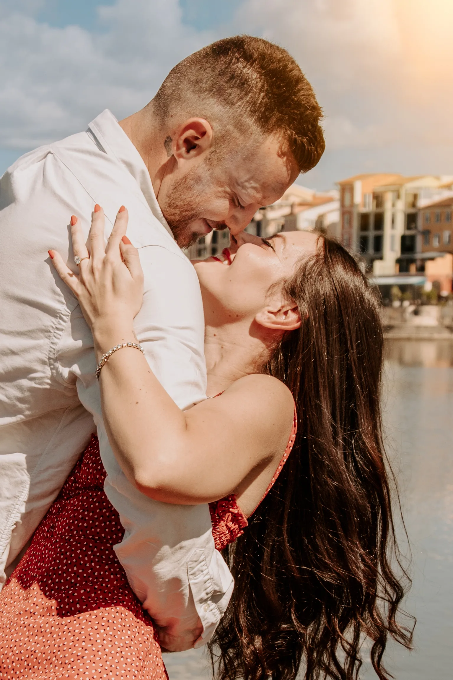 Romantic waterfront engagement kiss with colorful European buildings background