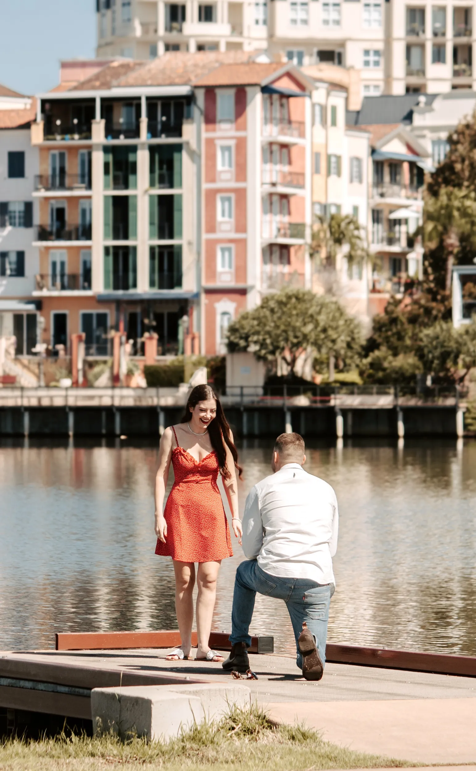 Daytime marriage proposal by colorful waterfront buildings with man kneeling