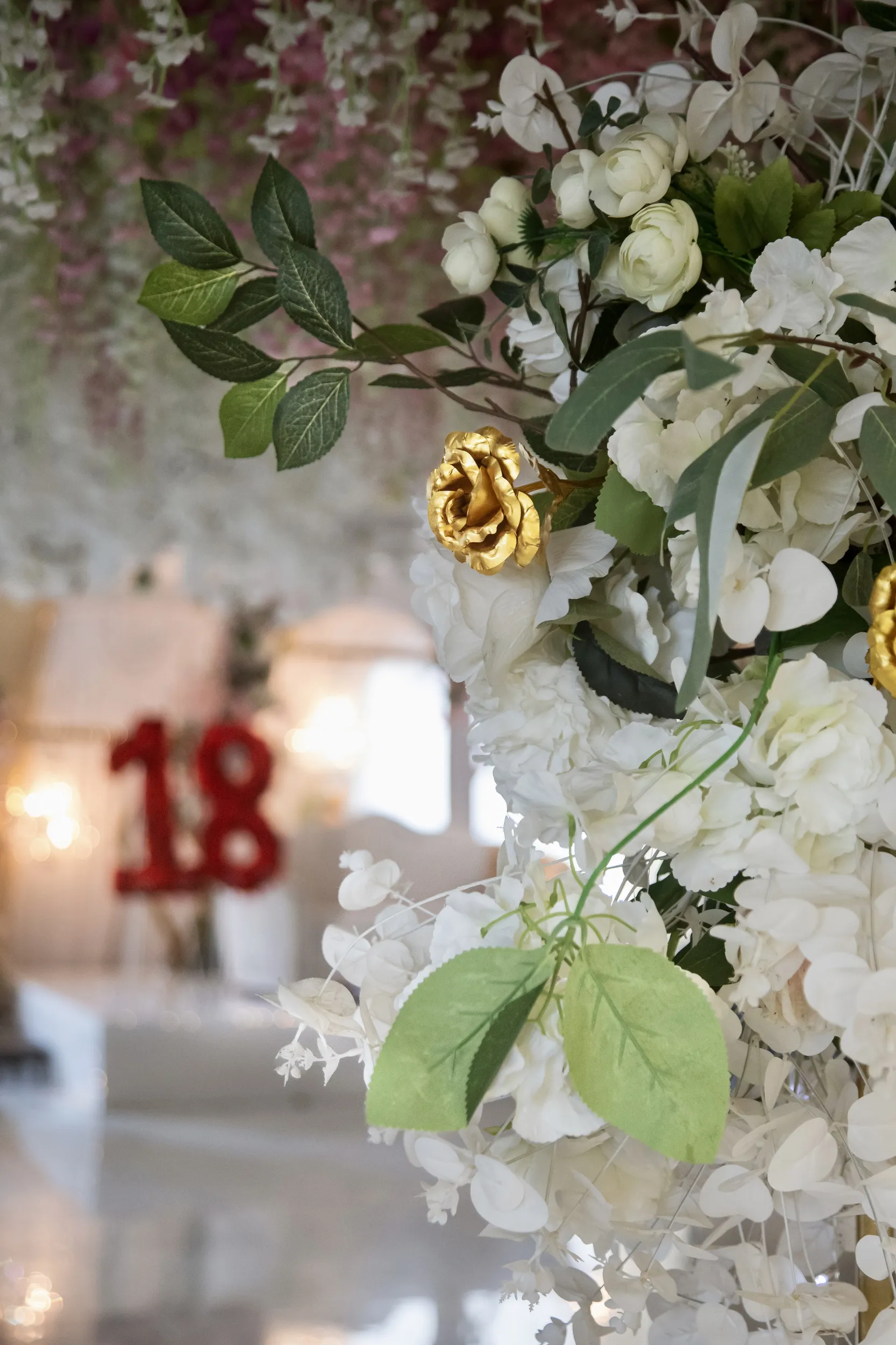 Artistic detail shot of white floral arrangements with golden rose accent for 18th birthday