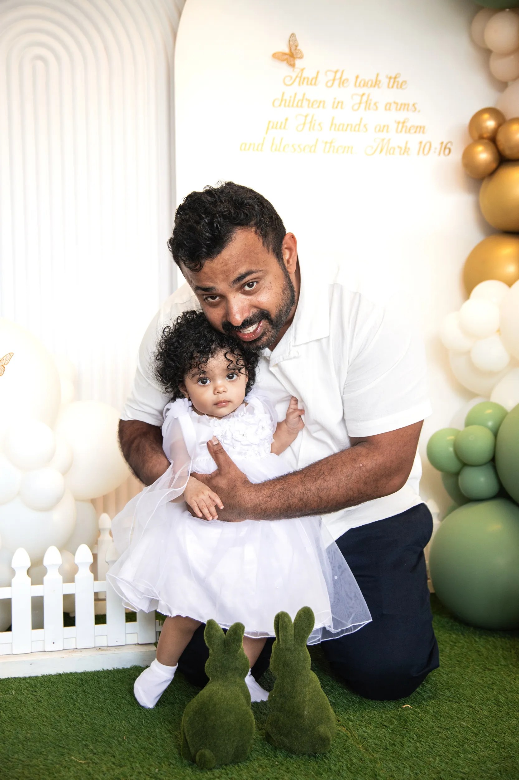 Heartwarming father-daughter portrait at baptism with biblical quote backdrop and balloon decorations