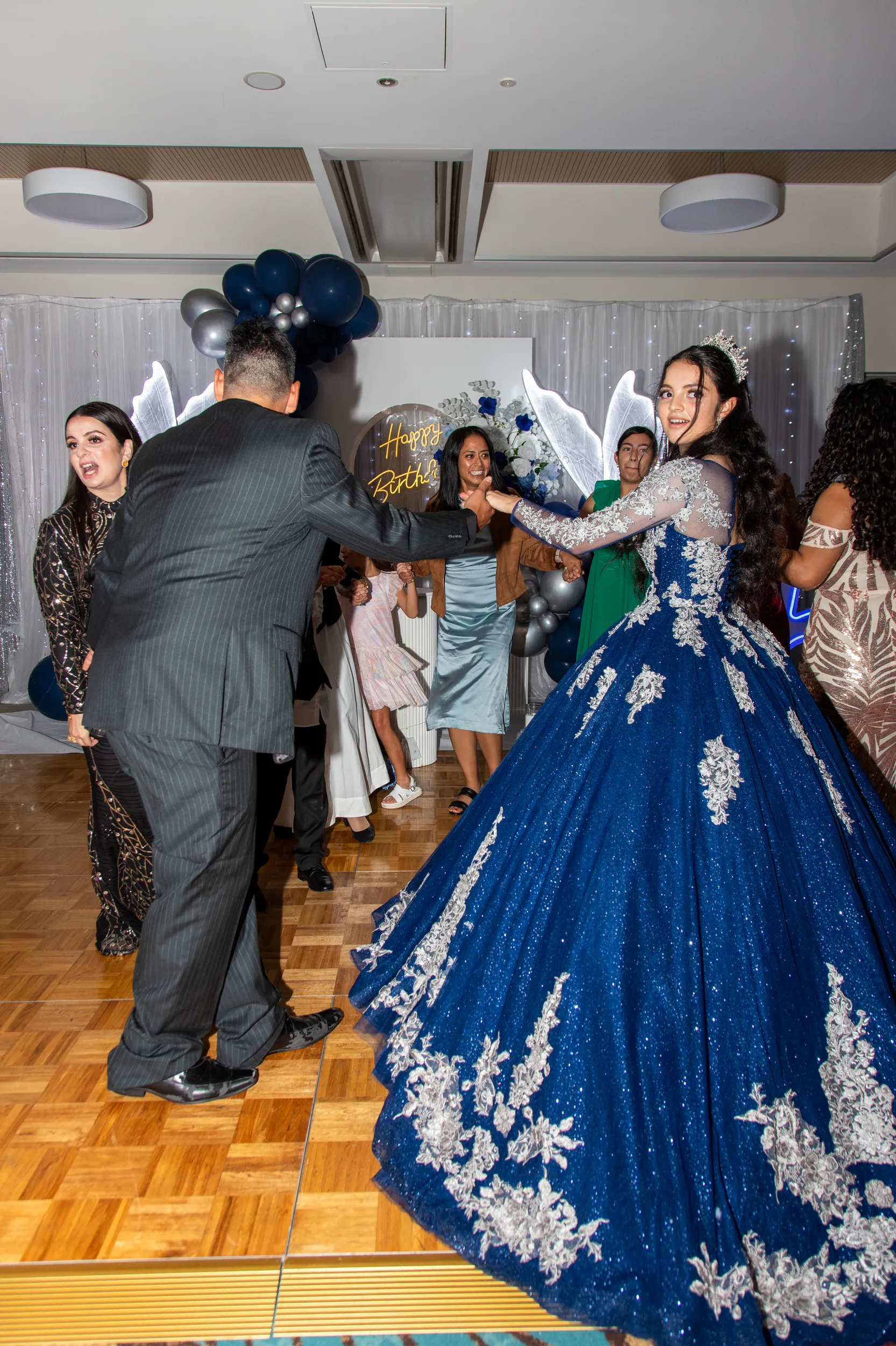 Lively debut celebration with father-daughter dance in blue ball gown surrounded by family