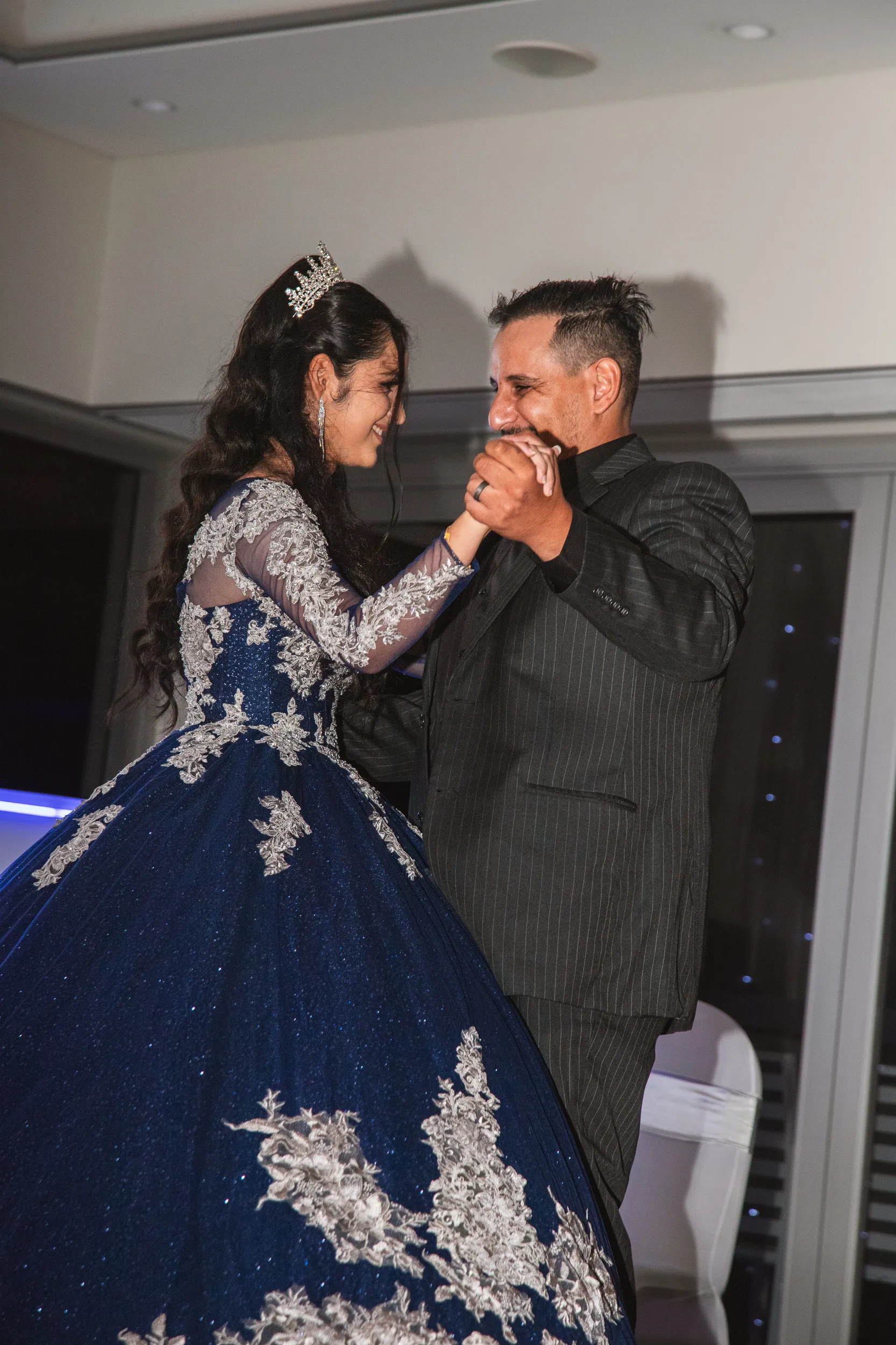 Intimate father-daughter dance moment at debut celebration in blue ball gown with elegant venue lighting