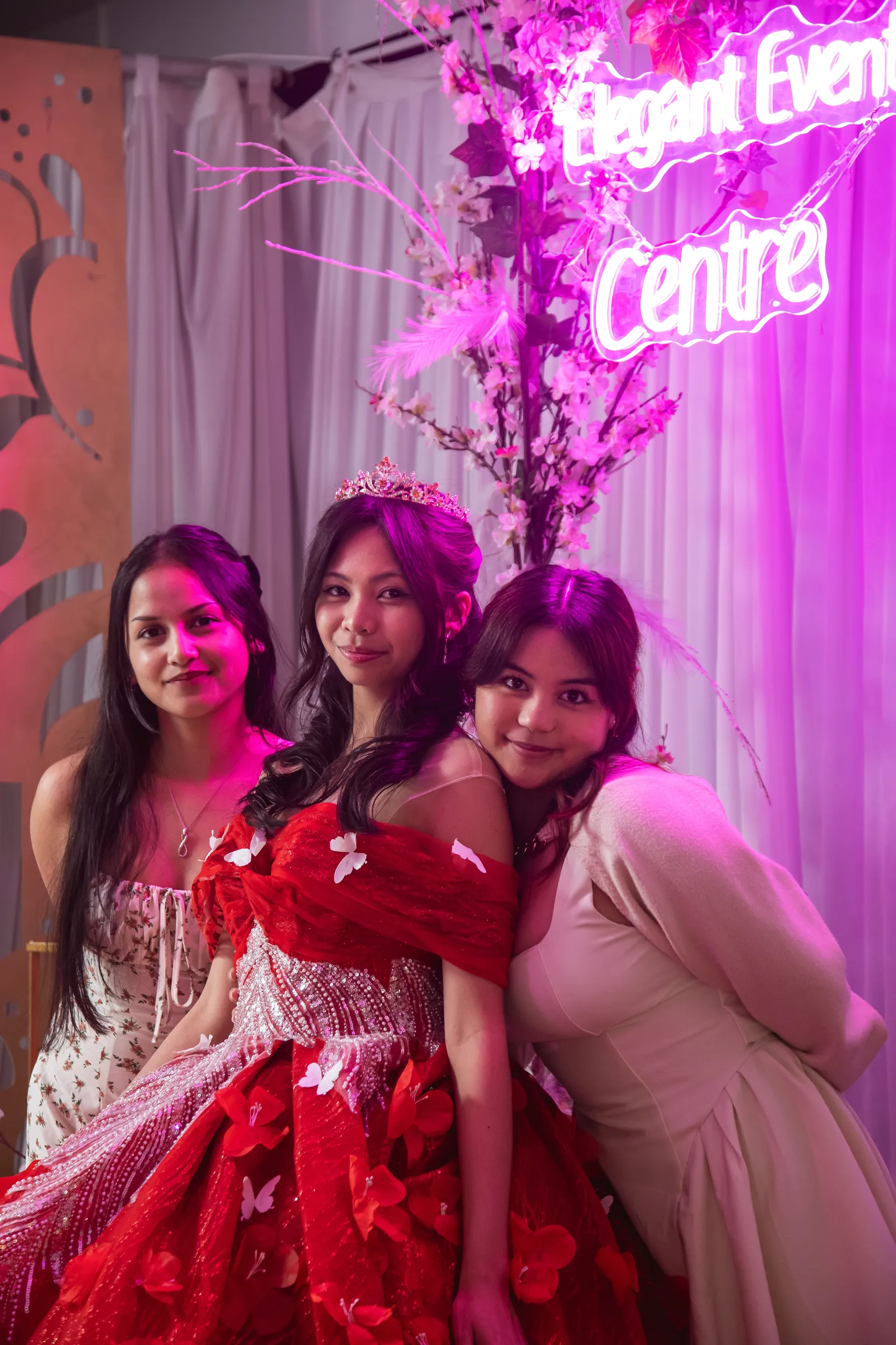 Group photo of three women at debut celebration under pink neon Event Centre lighting