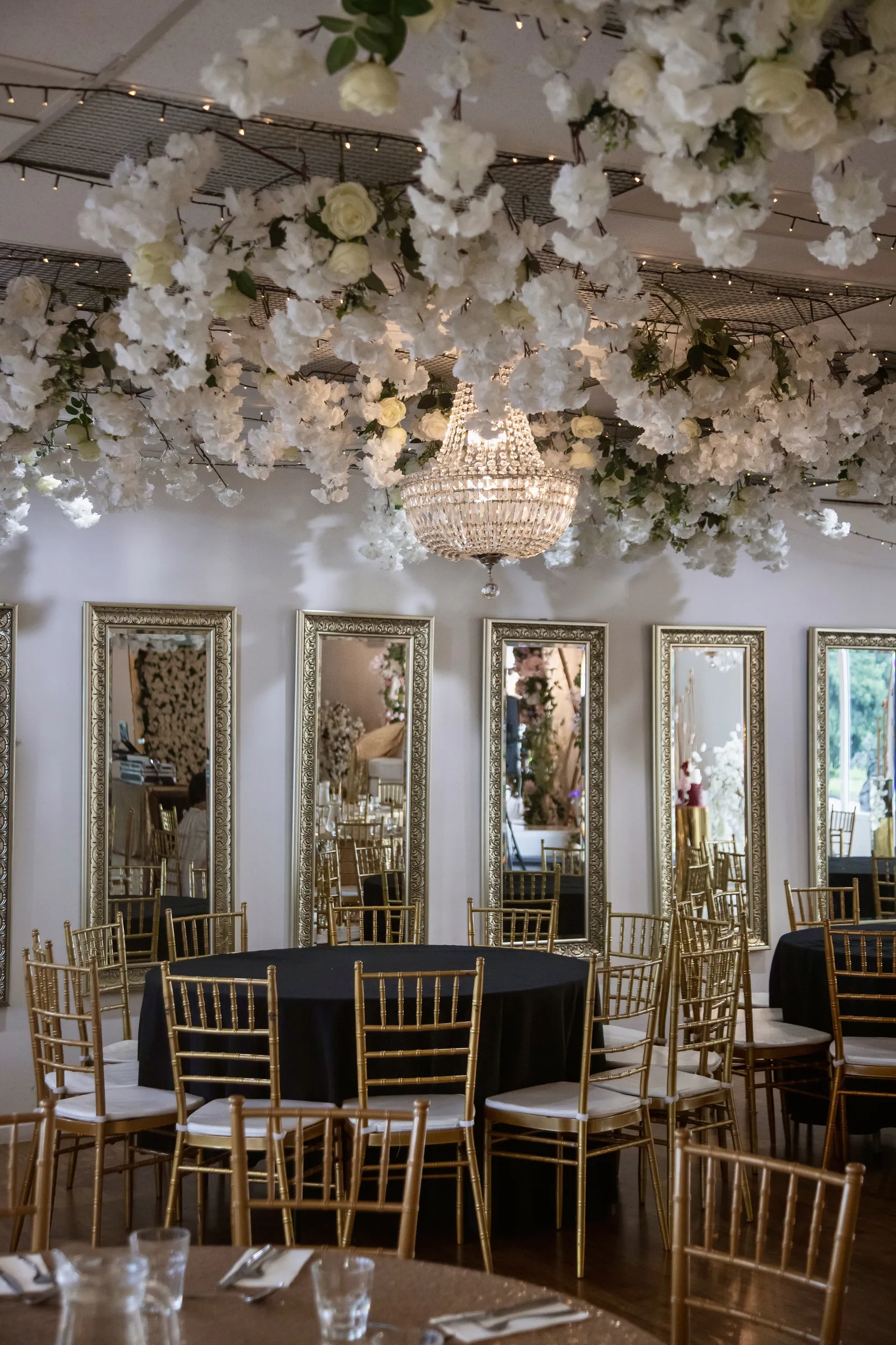 Stunning event venue with white floral ceiling, crystal chandeliers, and gold-framed mirrors