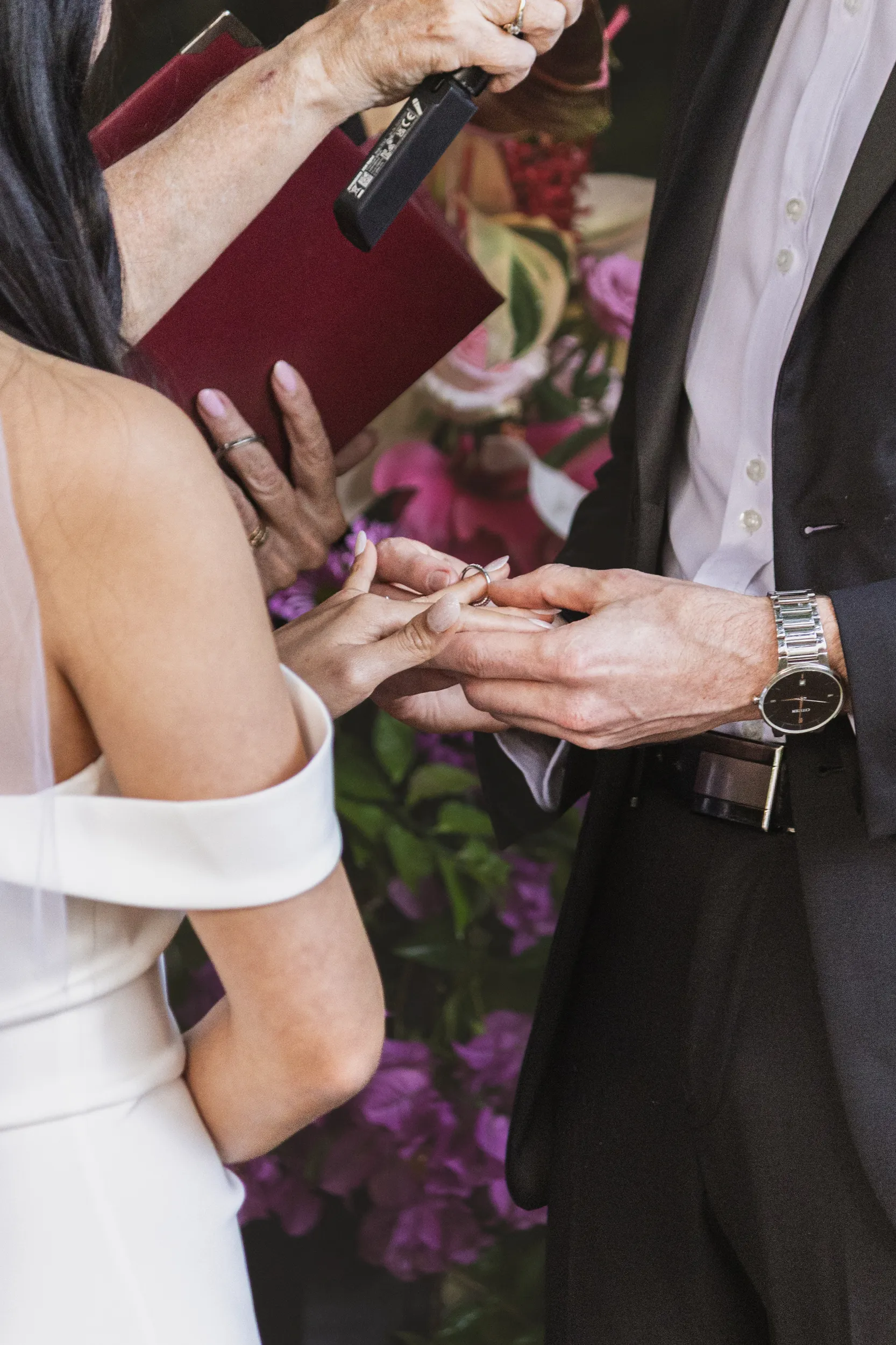 Huiyu and Chris intimate ring exchange ceremony detail with officiant holding burgundy book