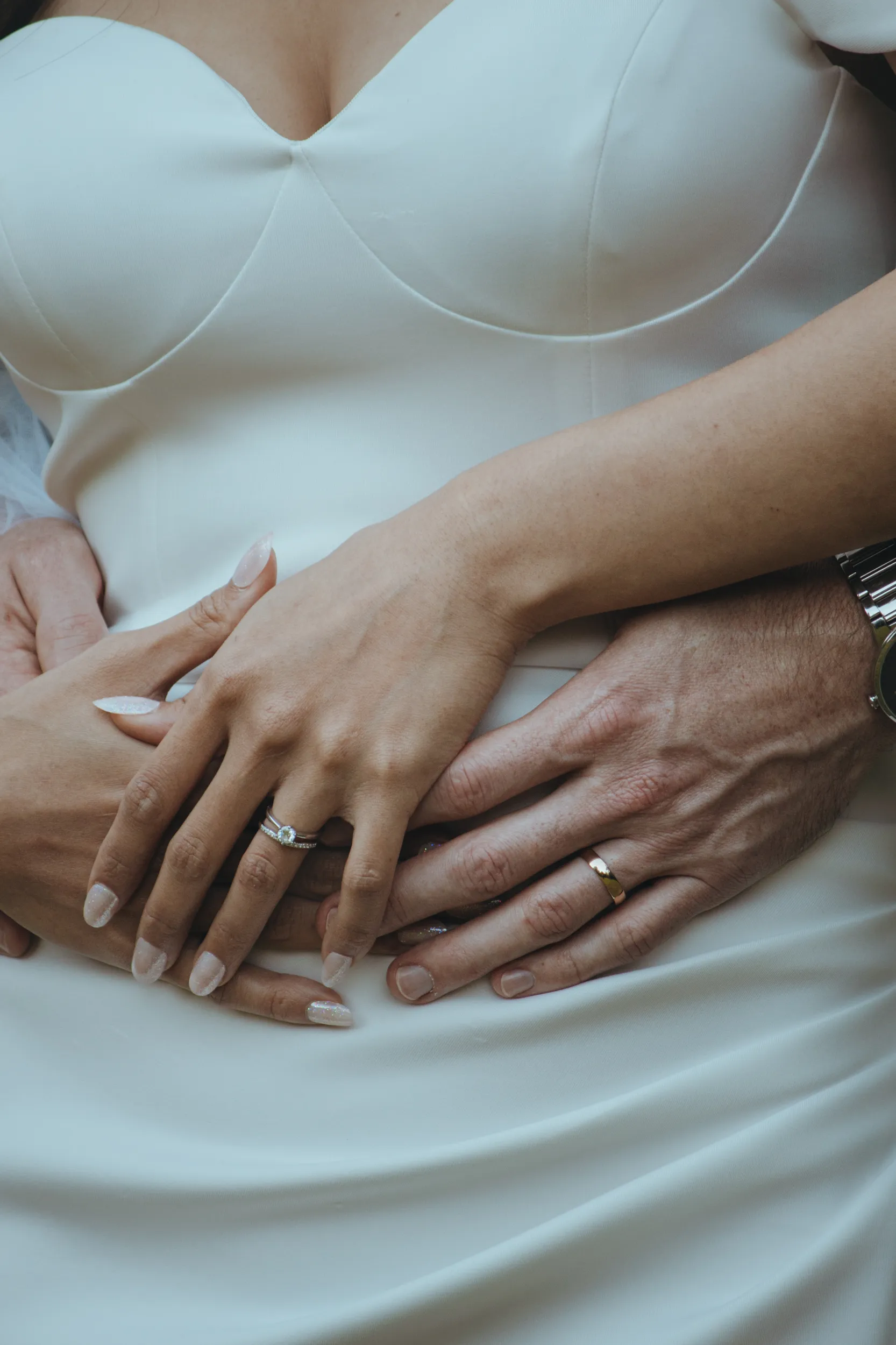 Huiyu and Chris intimate wedding detail shot of couple's hands showing engagement ring and wedding bands against white fabric