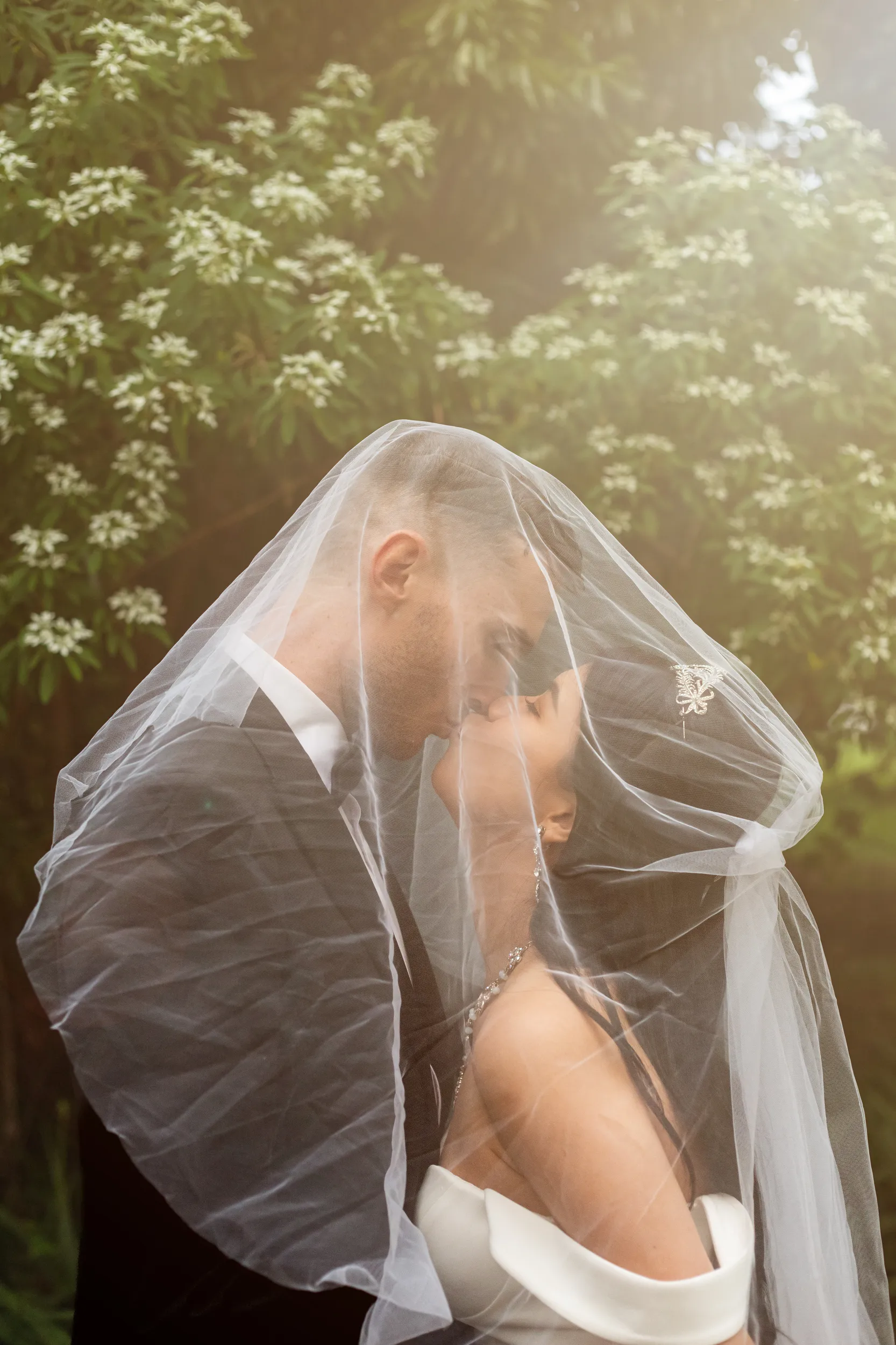 Huiyu and Chris dreamy ethereal moment embracing under bride's veil in golden hour lighting with beautiful backlighting