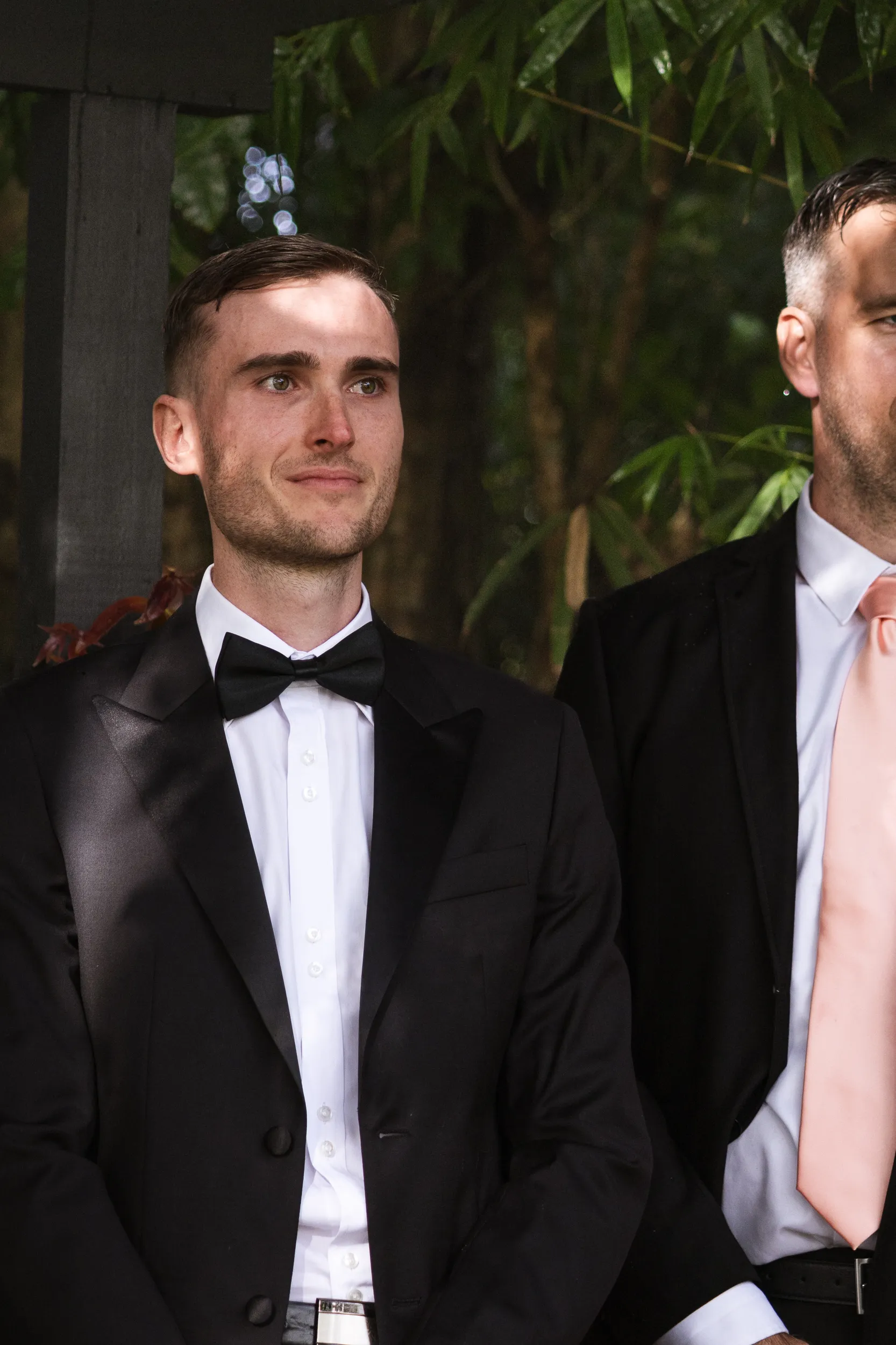 Chris and groomsmen formal portrait in black tuxedos with bow ties in lush garden setting