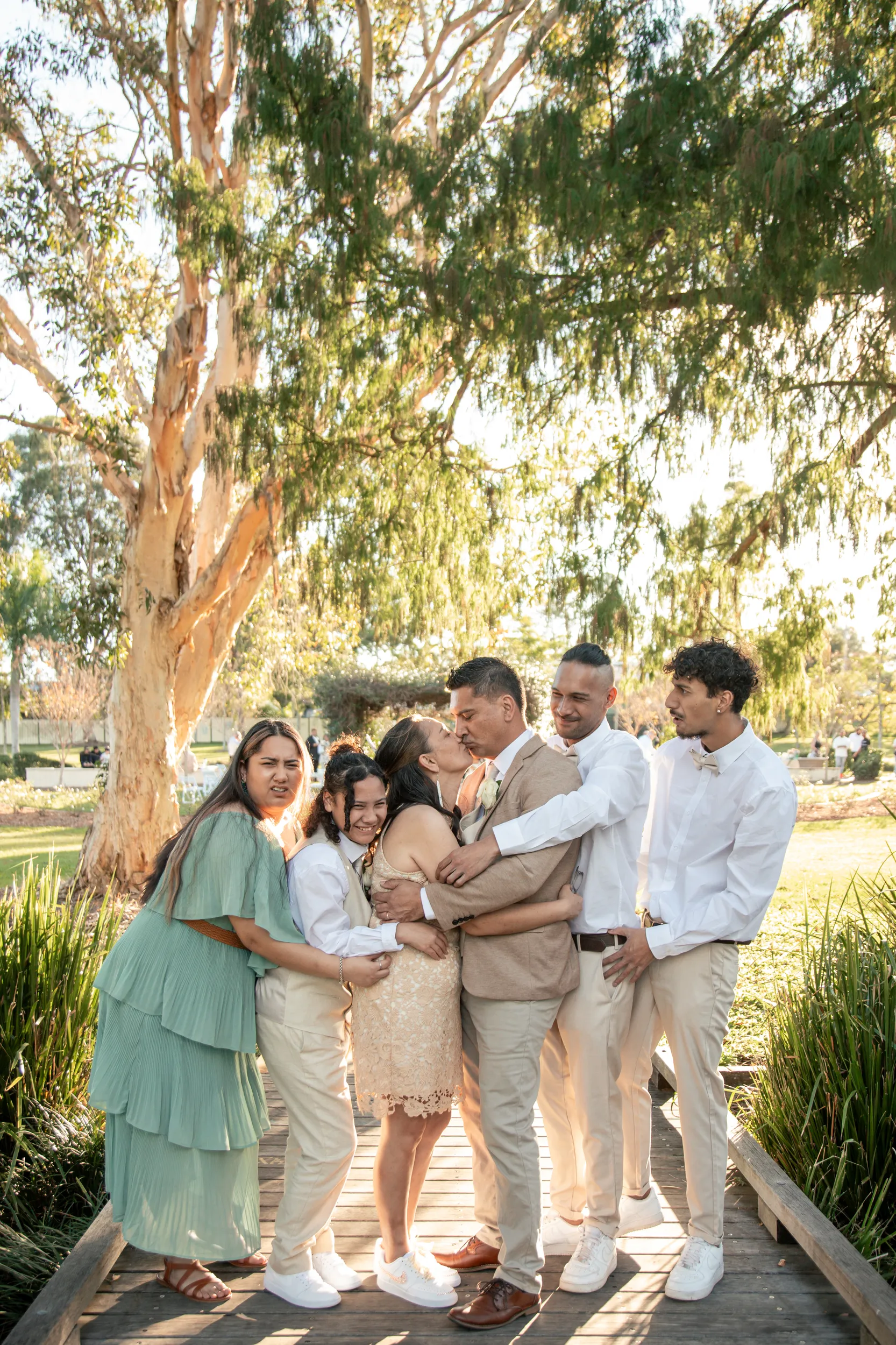 Heartwarming family group hug on wooden boardwalk with couple and children celebrating together
