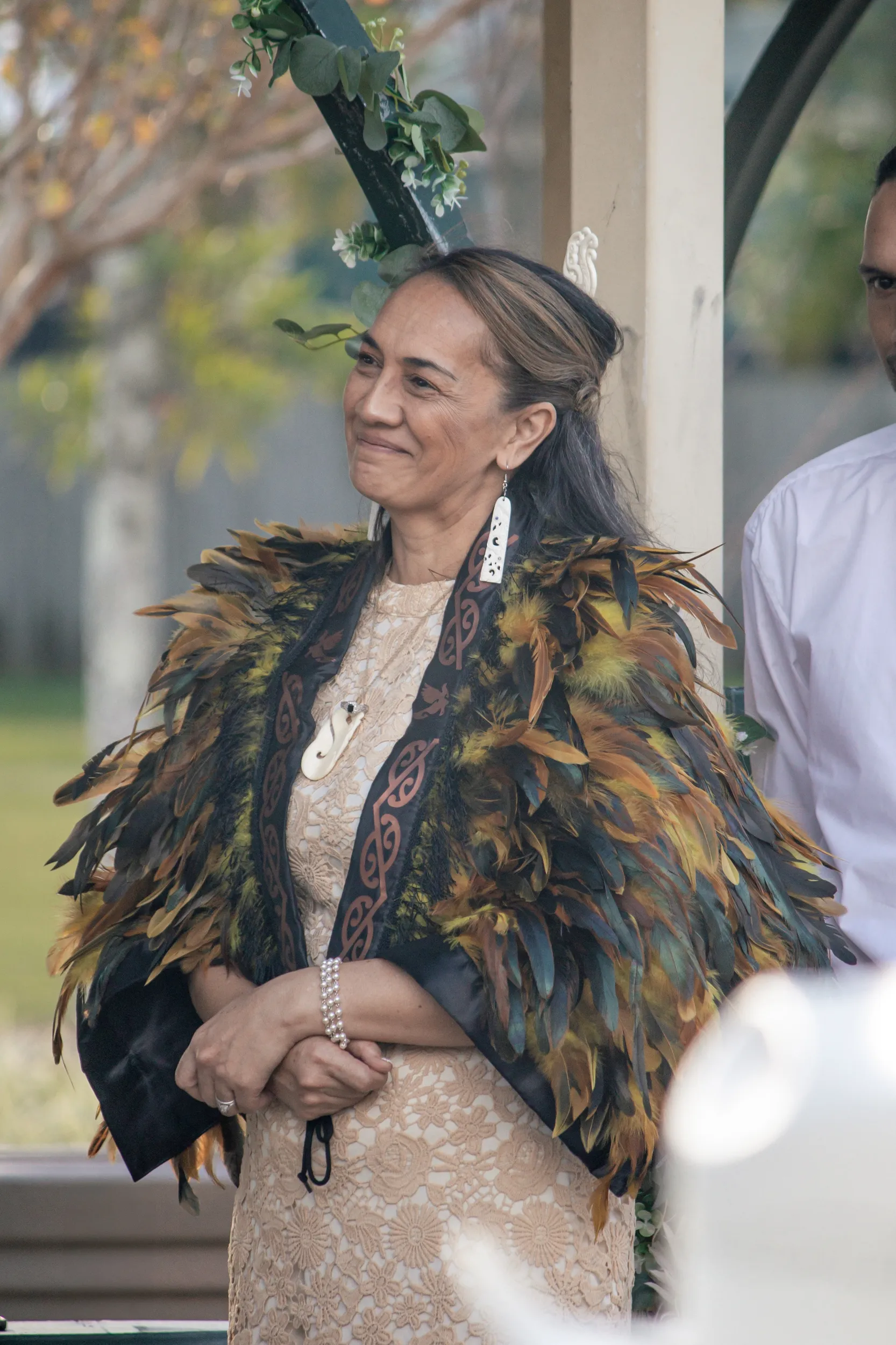 Beautiful portrait of bride in traditional Māori feather cloak (korowai) with greenery headpiece during cultural wedding ceremony