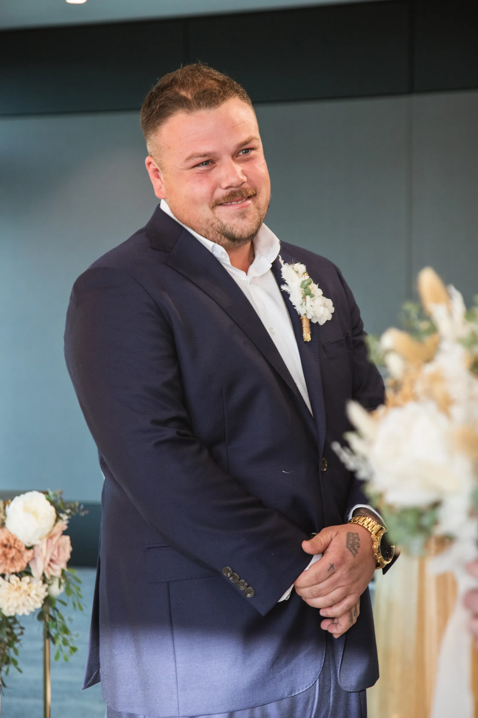Handsome groom portrait in navy blue suit with white boutonniere in elegant indoor venue